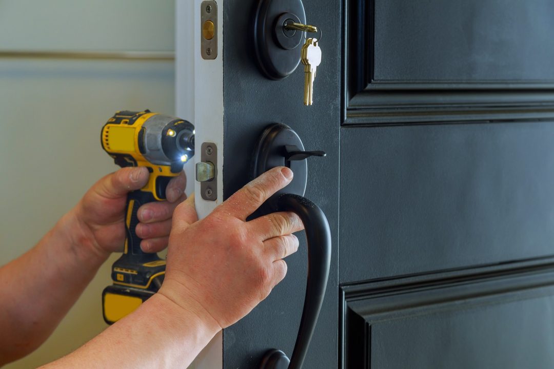 Home 1 closeup of a professional locksmith installing a new lock on a house exterior door with the inside